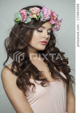 Attractive summer woman with long dark wavy hair, clean shiny skin and pink flower crown 115663098