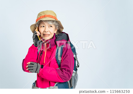 一位穿著登山服、受驚的老婦人用智慧型手機說話 一位穿著登山服、受驚的老婦人用智慧型手機說話 115663250