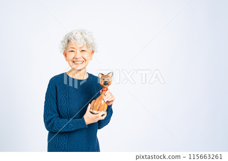 Senior woman holding a cat figurine Senior woman holding a cat figurine 115663261