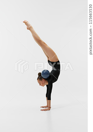 Flexible and artistic young girl, rhythmic gymnast showing skills and talent, training with ball isolated on white background. Flexible and artistic young girl, rhythmic gymnast showing skills and talent, training with ball isolated on white background. 115663530