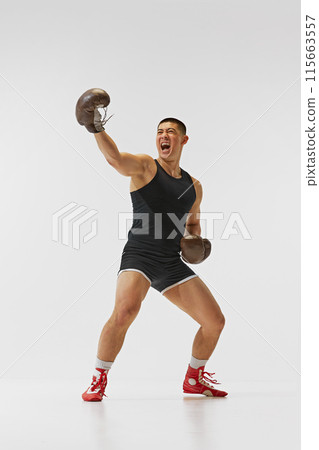 Achievement, success, victory. Full-length of emotions man, boxer in gloves showing his emotions after winning battle isolated on white background. 115663557