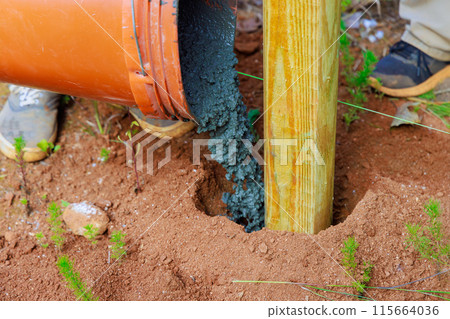 Construction of new timber fence and wooden fence posts using concrete 115664036