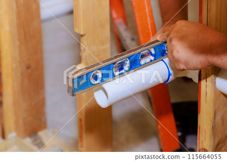 During gluing process, sanitary plastic PVC pipes are leveled using level 115664055