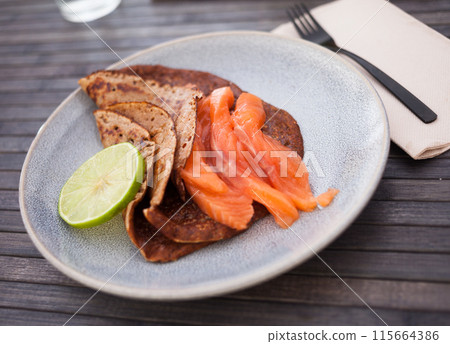 Salted salmon fillet with buckwheat pancakes and lime 115664386