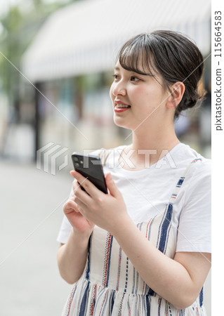 A young woman operating a smartphone 115664583