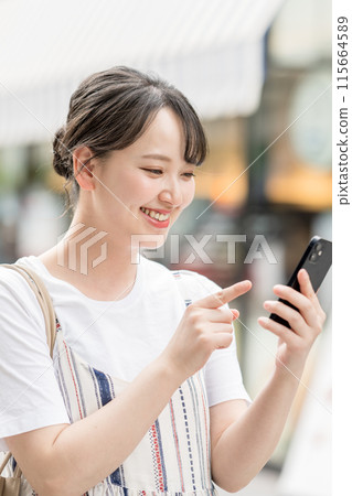 一個操作智能手機的年輕女子 115664589