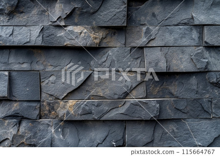 Stacked dark slate tiles with uneven surfaces create a rugged and dynamic textured wall pattern 115664767