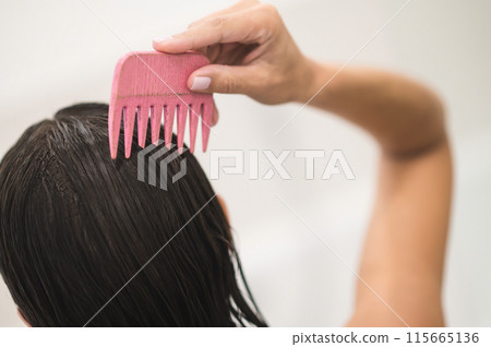 Dark-haired woman brushing her hair after shower Dark-haired woman brushing her hair after shower 115665136