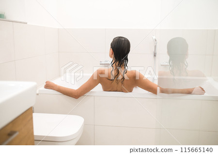 Woman sitting in the bath with her back to camera Woman sitting in the bath with her back to camera 115665140