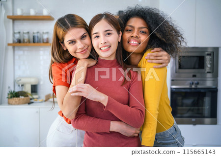 Three women are hugging each other in a kitchen Three women are hugging each other in a kitchen 115665143