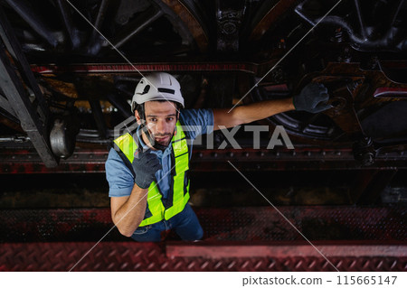 man in a yellow vest is standing on a platform, looking down at a train man in a yellow vest is standing on a platform, looking down at a train 115665147