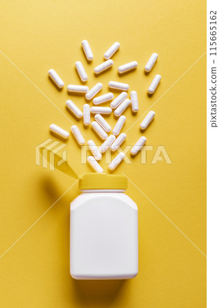 White medicine capsules on yellow background 115665162