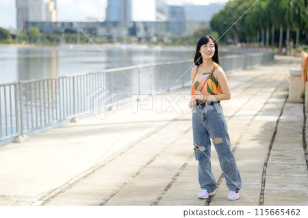 A happy young woman, enjoying a stroll on an urban path, dressed in an orange shirt. 115665462