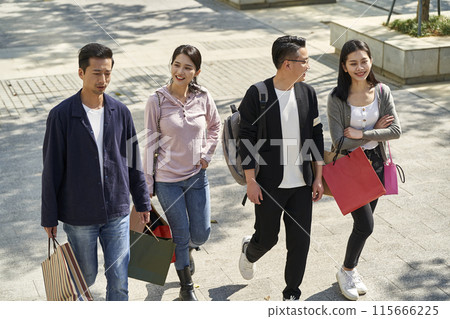 group of young asian people talking chatting conversing while walking on street with shopping bags 115666225