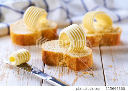 Butter curls on a slice of baguette bread on a wooden table,selective focus. 115666860
