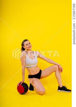 Fitness happy fit woman standing holding a medicine ball. Slim caucasian cross fit woman with fitness ball 115667190