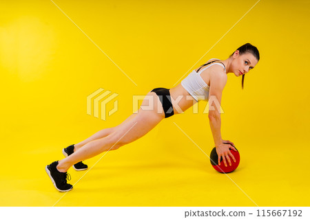 Fitness happy fit woman standing holding a medicine ball. Slim caucasian cross fit woman with fitness ball Fitness happy fit woman standing holding a medicine ball. Slim caucasian cross fit woman with fitness ball 115667192