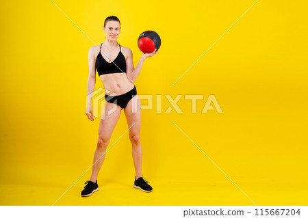 Fitness happy fit woman standing holding a medicine ball. Slim caucasian cross fit woman with fitness ball 115667204