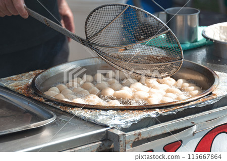 Cook is preparing a Loukoumades dough balls in boiling oil. Cyprus 115667864
