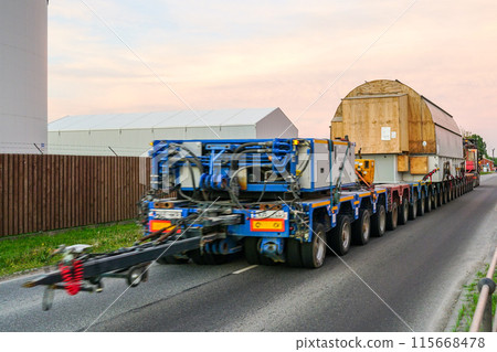 Very long specialized multi axle truck trailer carries very heavy oversize cargo, rear view 115668478