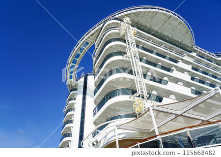 High back of a large cruise ship with balconies on a blue sky background, ship hull washing facility 115668482