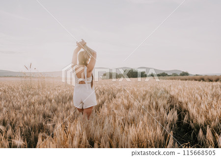 Woman wheat field. Agronomist, Woman farmer check golden ripe barley spikes in cultivated field. A woman is holding a bunch of wheat in her arms. 115668505