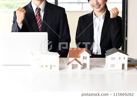 Male and female employees of a real estate company doing a fist pump 115669262
