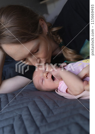 A tender moment of a mother kissing her newborn baby, capturing pure love and warmth 115669493