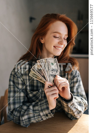 Vertical portrait of happy excited successful young student female holding money dollar bills in hand looking up dreaming. Positive emotion facial expression feeling. Financial reward 115669577