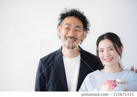 A man and a woman holding a bouquet of flowers - for a wedding anniversary or a special occasion A man and a woman holding a bouquet of flowers - for a wedding anniversary or a special occasion 115672415