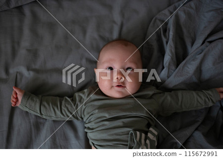 An adorable baby smiling happily while lying down, capturing a moment of pure innocence 115672991