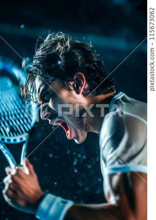 A man is holding a tennis racket and is in the middle of a match 115673062