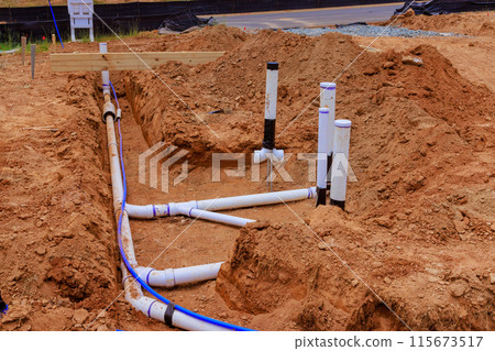 Laying underground water pipes sanitary pipes prior to pouring concrete in foundation of new residence 115673517