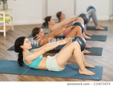 Young woman doing crunches with ball during group Pilates class 115673874