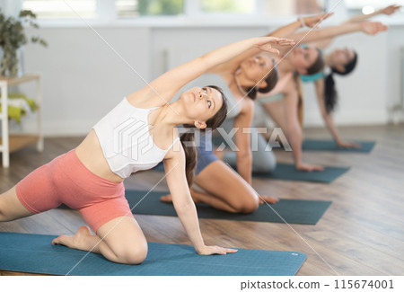Young girl practicing Gate Pose during group yoga session Young girl practicing Gate Pose during group yoga session 115674001