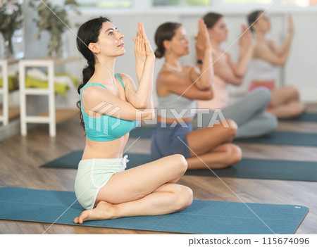 Young girl performing Cow face pose with eagle arms at yoga class 115674096