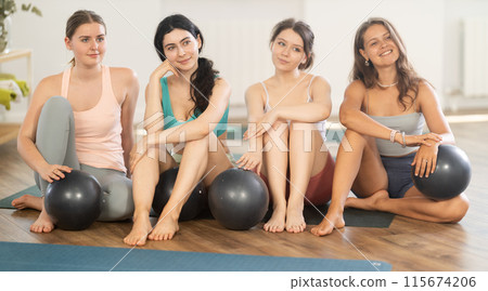 Young girl yoga instructor in company of female students poses for group photo with fitness balls 115674206