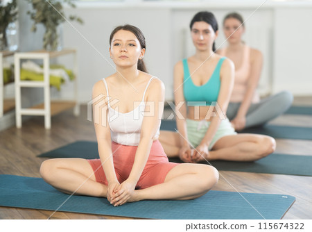 Meditation in lotus position during yoga class in studio. Women meditating Meditation in lotus position during yoga class in studio. Women meditating 115674322