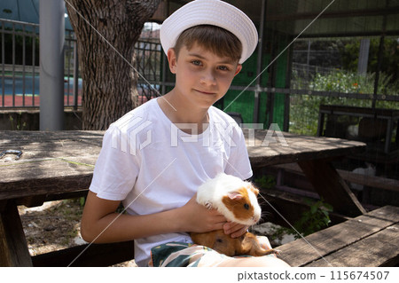 Boy holding a guinea pig in his arms Boy holding a guinea pig in his arms 115674507