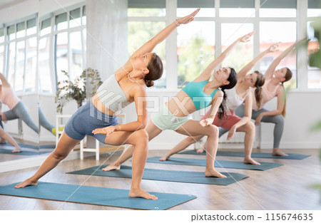 Young girl performing Extended Side Angle Pose at group yoga session 115674635