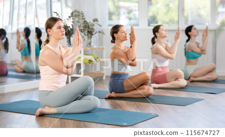 Young girl performing Cow face pose with eagle arms at yoga class 115674727