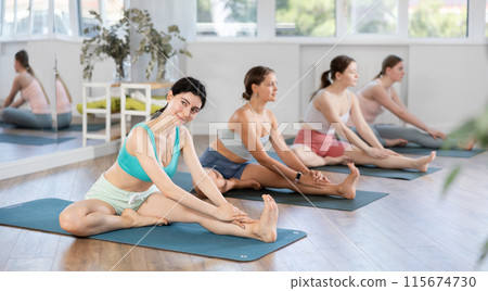 Sporty girl doing stretching in Janu Sirsasana in yoga studio 115674730