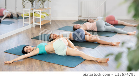 Young girl doing Supta Matsyendrasana during group yoga practice Young girl doing Supta Matsyendrasana during group yoga practice 115674795