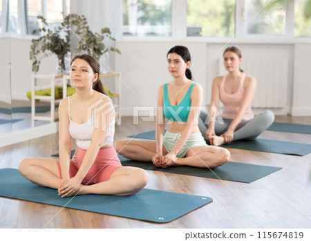 Meditation in lotus position during yoga class in studio. Women meditating Meditation in lotus position during yoga class in studio. Women meditating 115674819