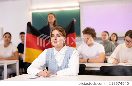 Teacher stands behind students with German flag Teacher stands behind students with German flag 115674940
