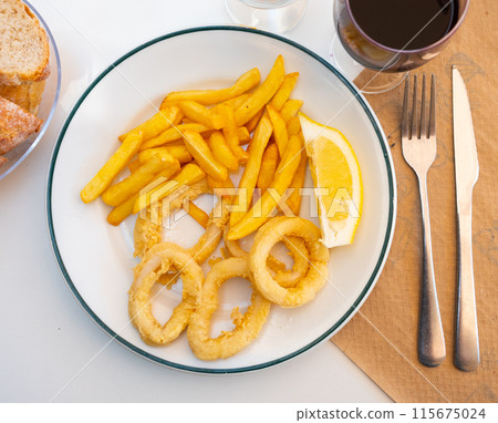 Deep-fried coated squid rings served with lemon and fries 115675024