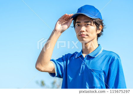 A young male driver in work clothes wearing a hat 115675297