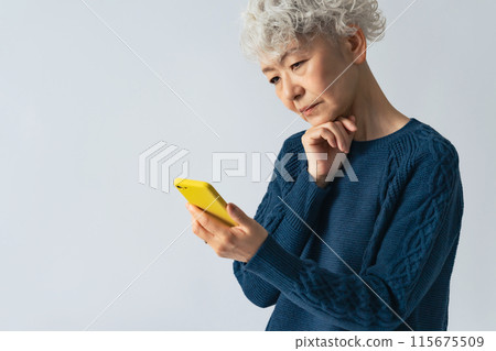 Senior woman worried while using a smartphone 115675509