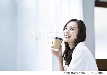 Young woman drinking coffee by the window 115677086