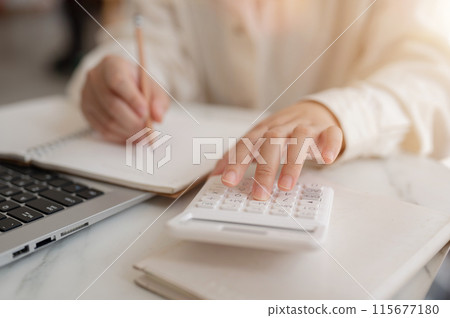 A close-up image of a woman using a calculator, examining her expenses, planning her savings A close-up image of a woman using a calculator, examining her expenses, planning her savings 115677180